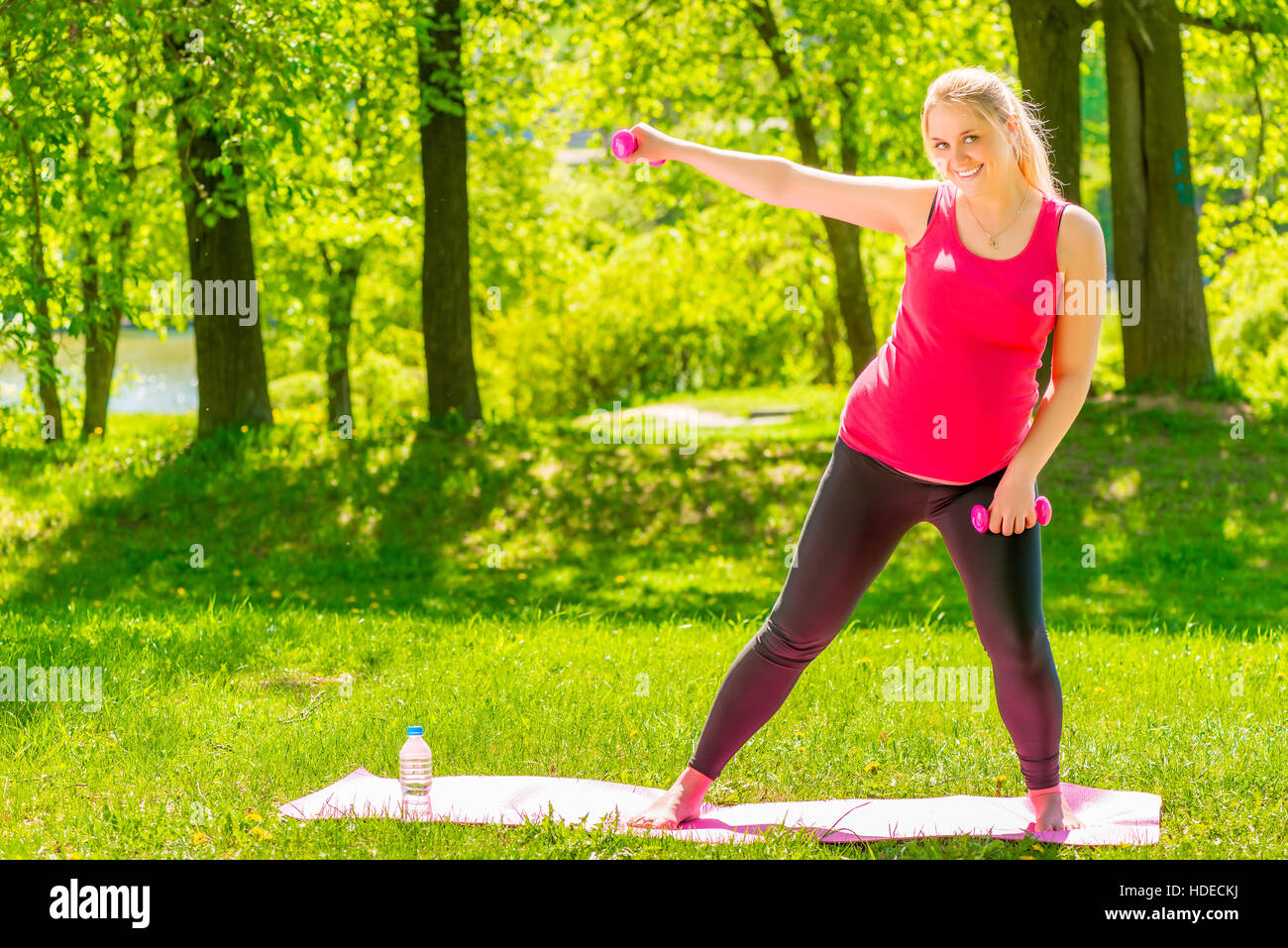 Schwangere Frau mit Hanteln machen Sport auf dem Rasen im park Stockfoto