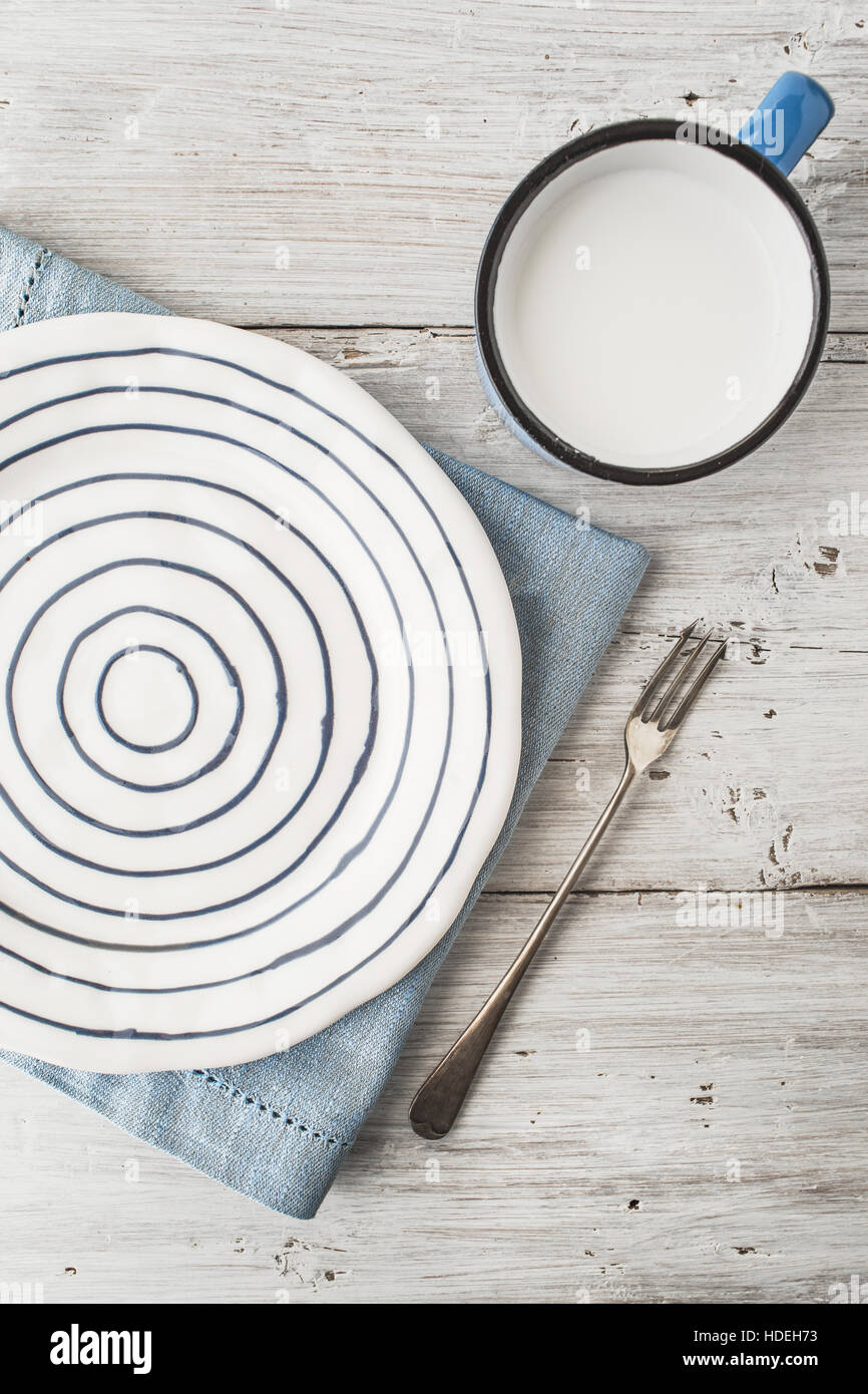 Keramikplatte mit Gabel und Tasse Milch auf dem Holztisch vertikale Stockfoto