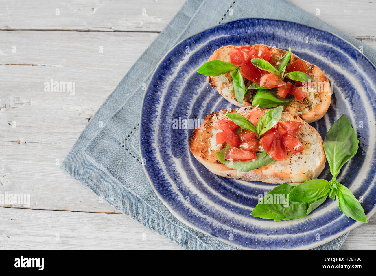 Bruschetta mit Tomaten und Basilikum auf der horizontalen Keramikplatte Stockfoto