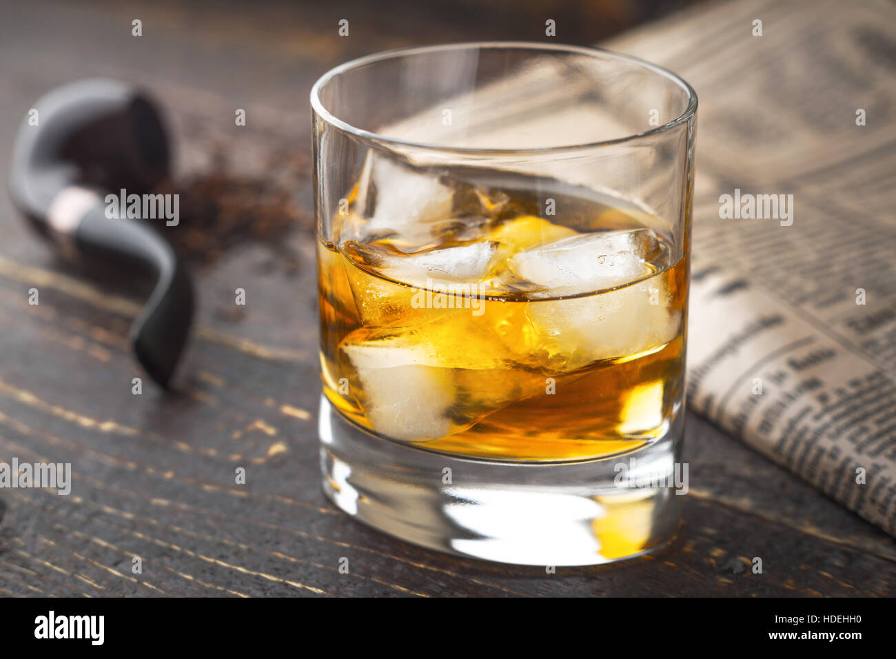 Whisky mit Eis und unscharfen Rohr und Zeitung Stockfoto