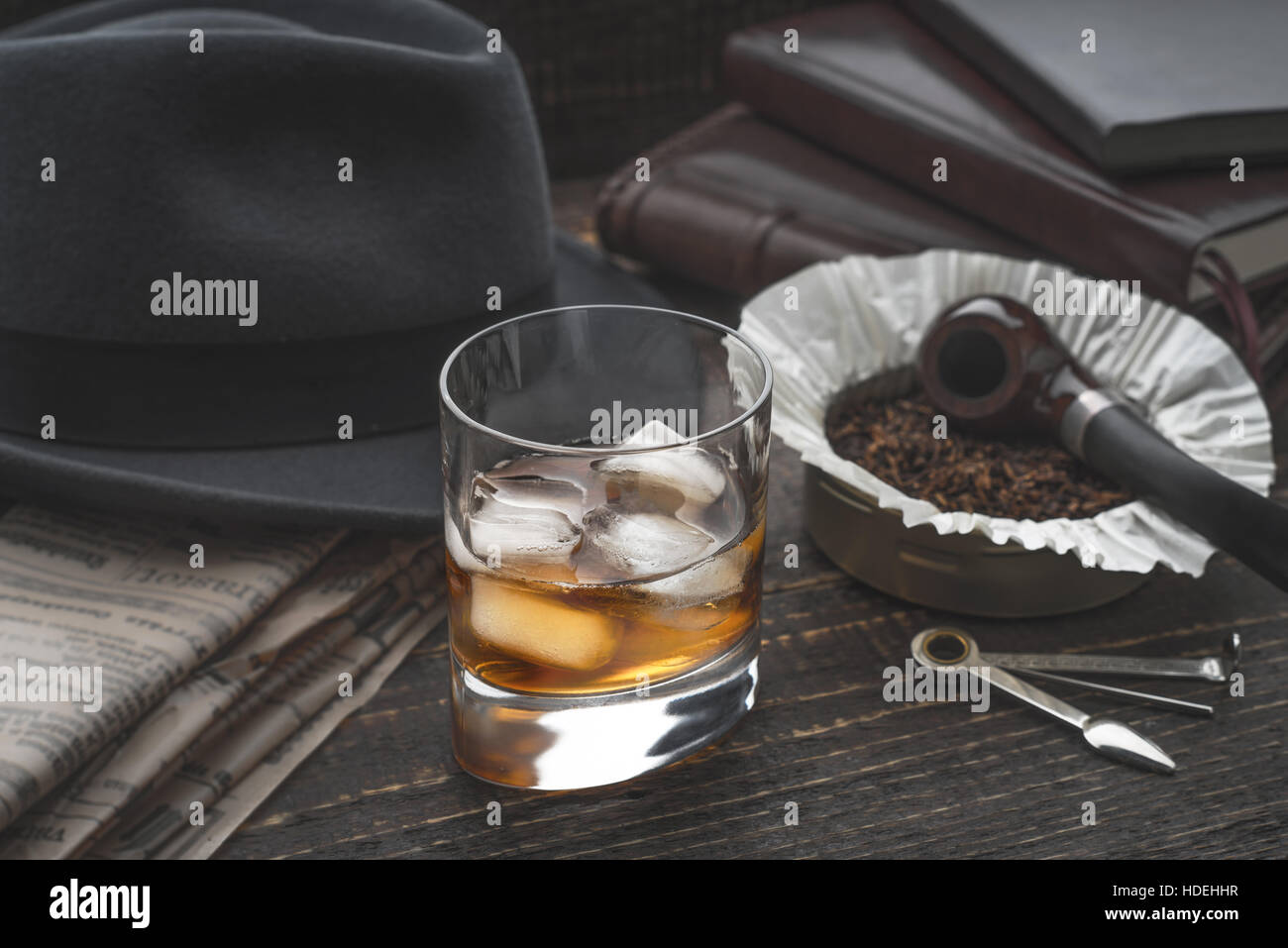 Whisky mit Eis, Rohr-Hut und Zeitung Stockfoto