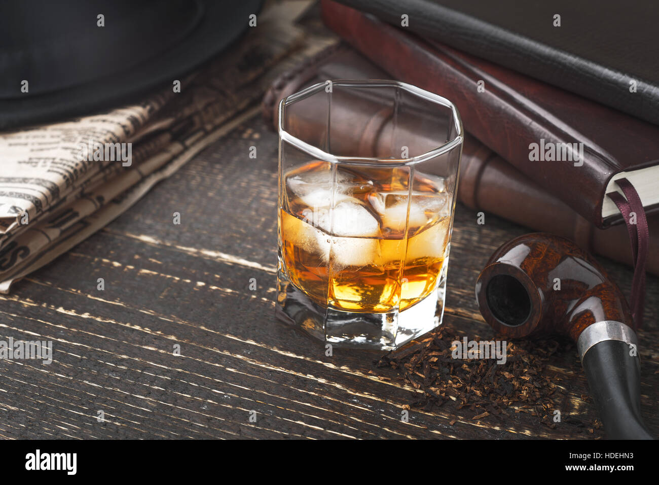 Whisky mit Rohr, Hut und Zeitung auf dem Holztisch Stockfoto