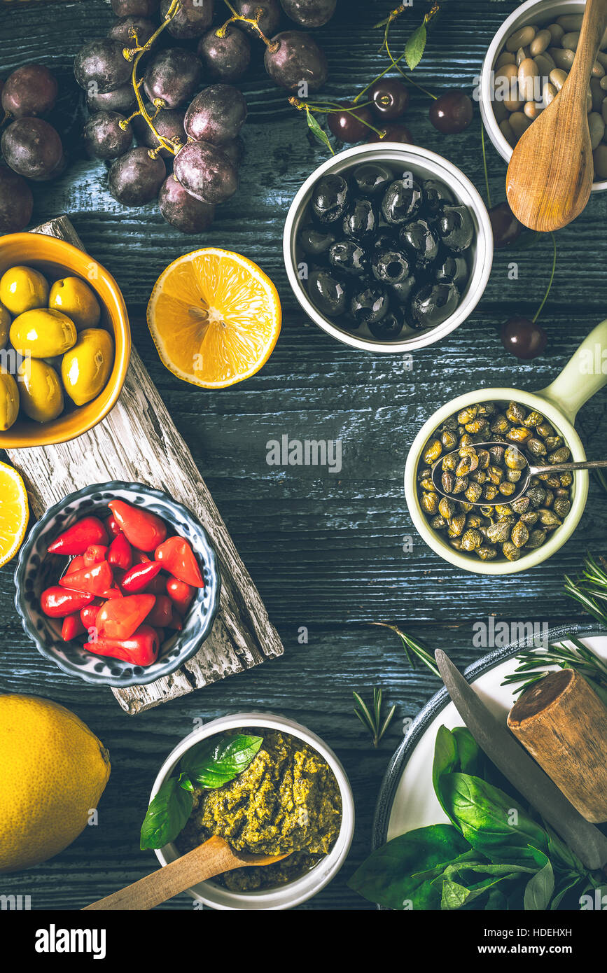 Konzept der mediterranen Küche. Verschiedene Früchte, Kräuter und Vorspeisen auf dem Holztisch vertikale Stockfoto