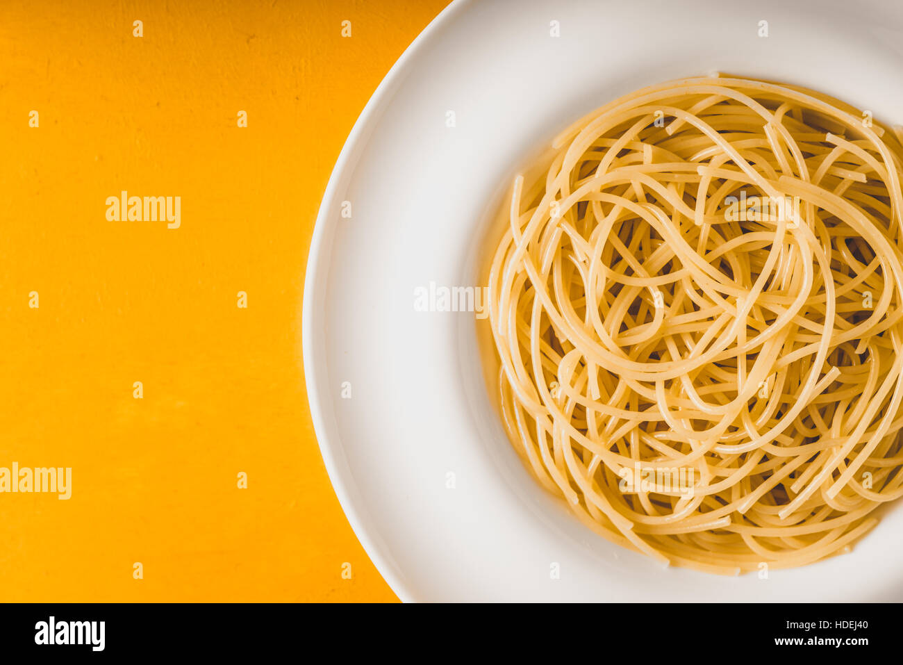 Spaghetti auf den weißen Teller auf gelbem Hintergrund-Draufsicht Stockfoto