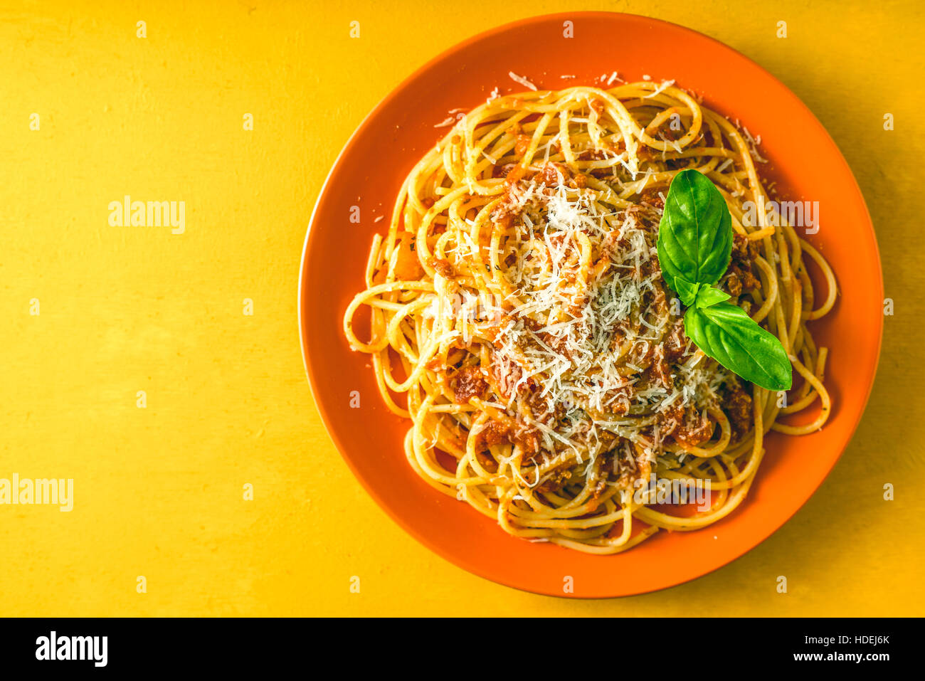Spaghetti Bolognese auf dem orange Teller auf gelbem Hintergrund-Draufsicht Stockfoto