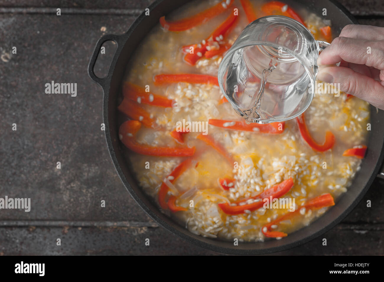 Zugabe von Wasser in der Pfanne mit Reis und Paprika Draufsicht Stockfoto