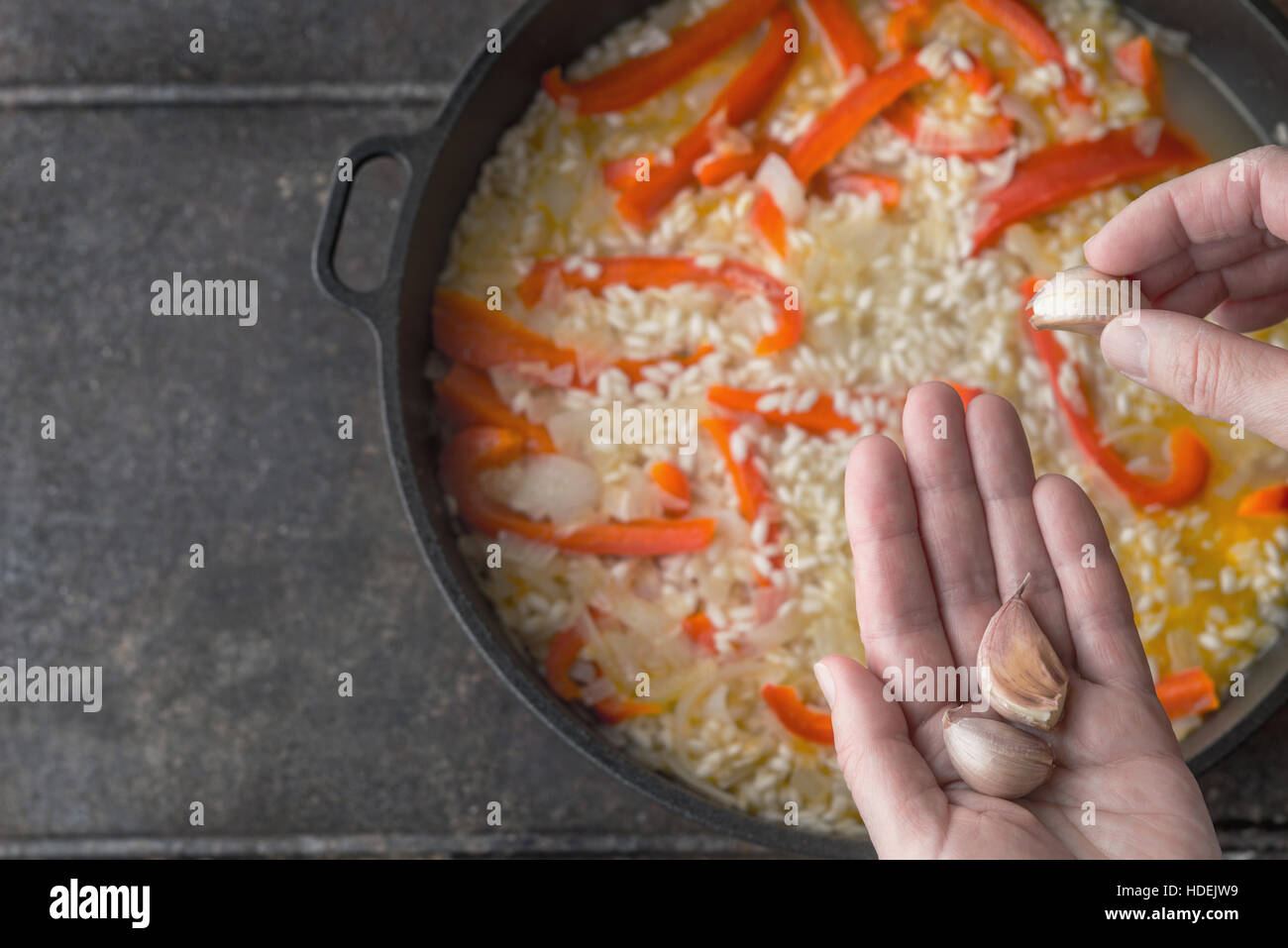 Hinzufügen von Knoblauch in der Pfanne mit Reis und Paprika Draufsicht Stockfoto