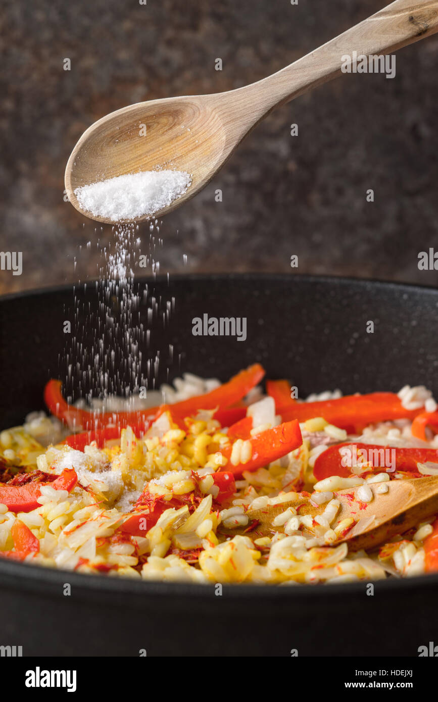 Zugabe von Salz in der Pfanne mit Reis und Paprika vertikale Stockfoto