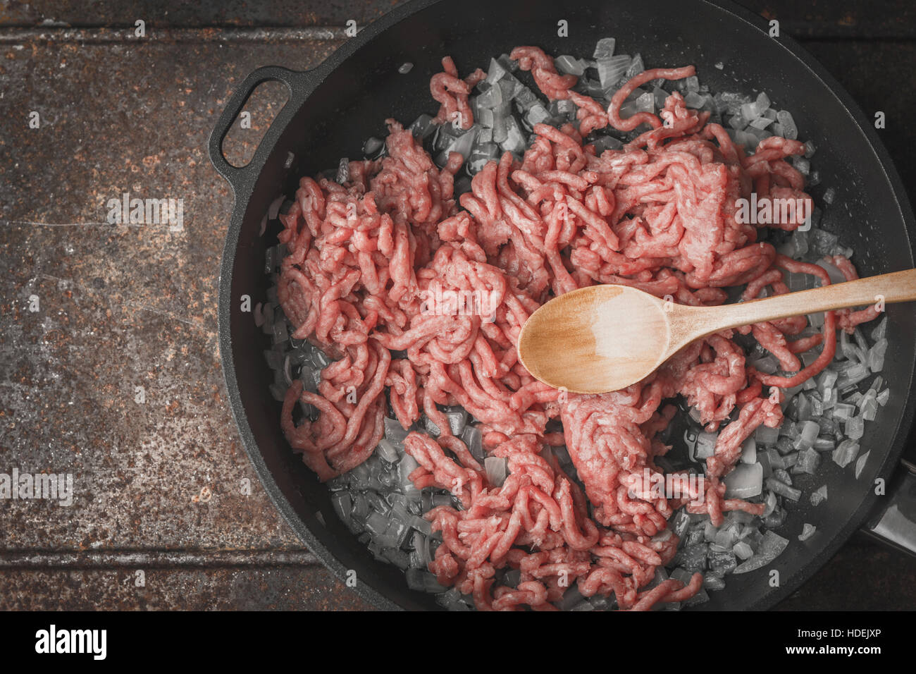 Rohes Hackfleisch mit in Scheiben geschnittenen Zwiebeln in der Pfanne-Draufsicht Stockfoto