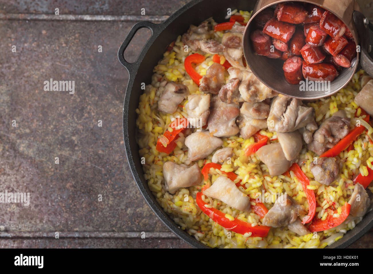 Hinzufügen von geräucherte Würstchen auf der Pfanne mit Kochen Paella Draufsicht Stockfoto