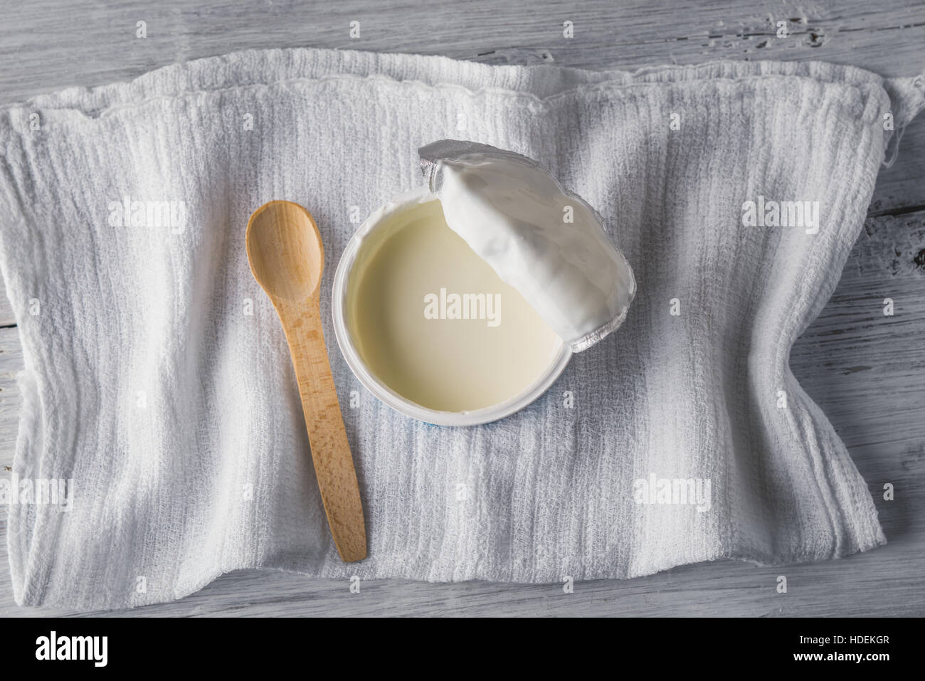 Naturjoghurt mit Löffel und Serviette auf weißer Holztisch Stockfoto