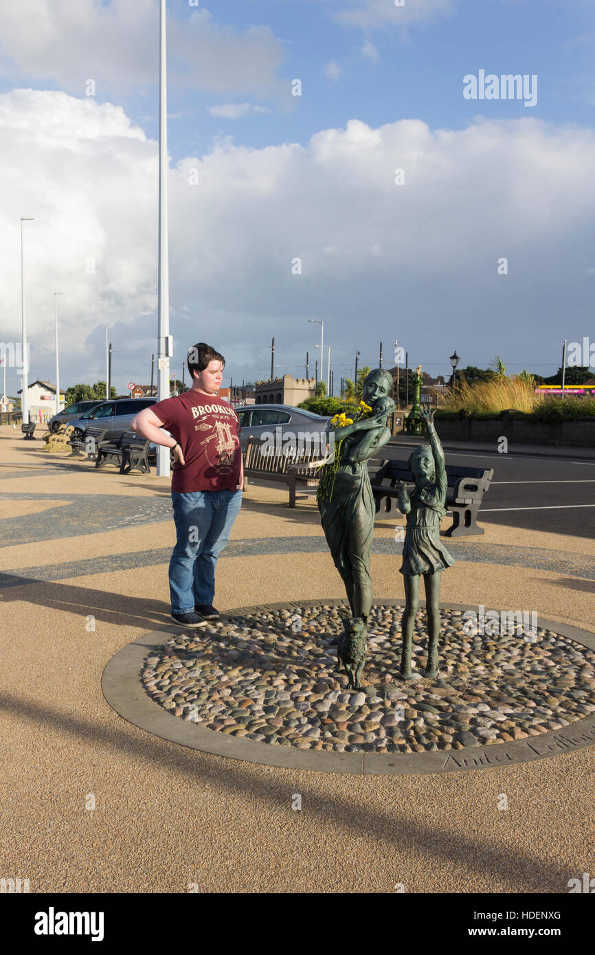 Junger Mann auf der Esplenade, Fleetwood, die Skulptur "Welcome Home" von Anita Lafford anzeigen. Stockfoto