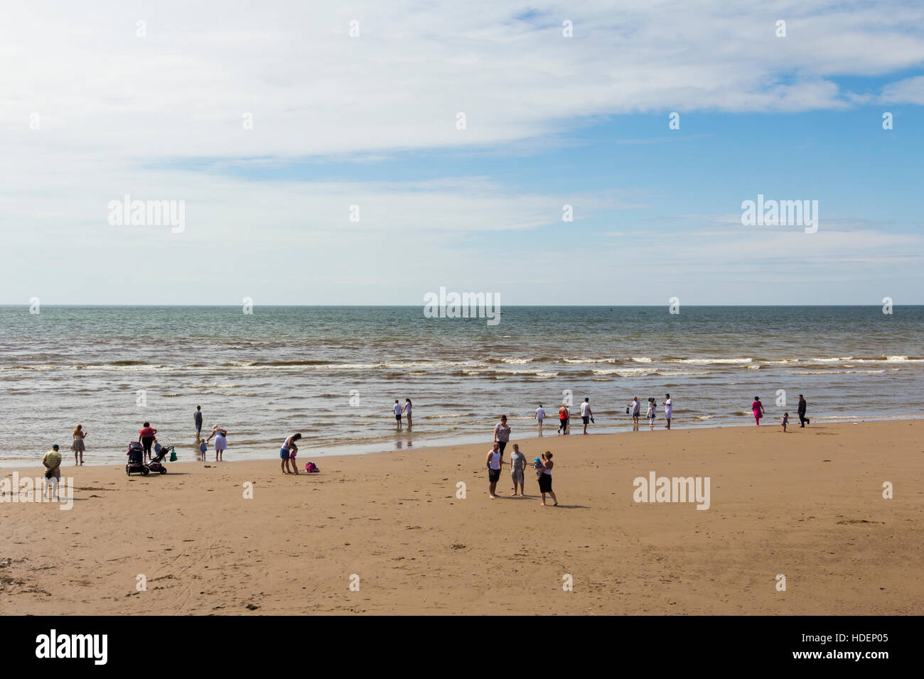 Eine kleine Zahl der Besucher am Strand von Blackpool, Paddeln im Meer bei Ebbe. Stockfoto