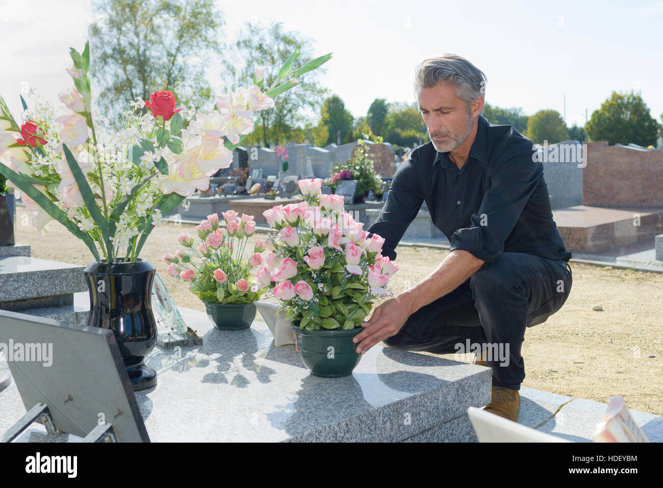 Mann, die Hinterlegung von Blumen auf ein Grab Stockfoto