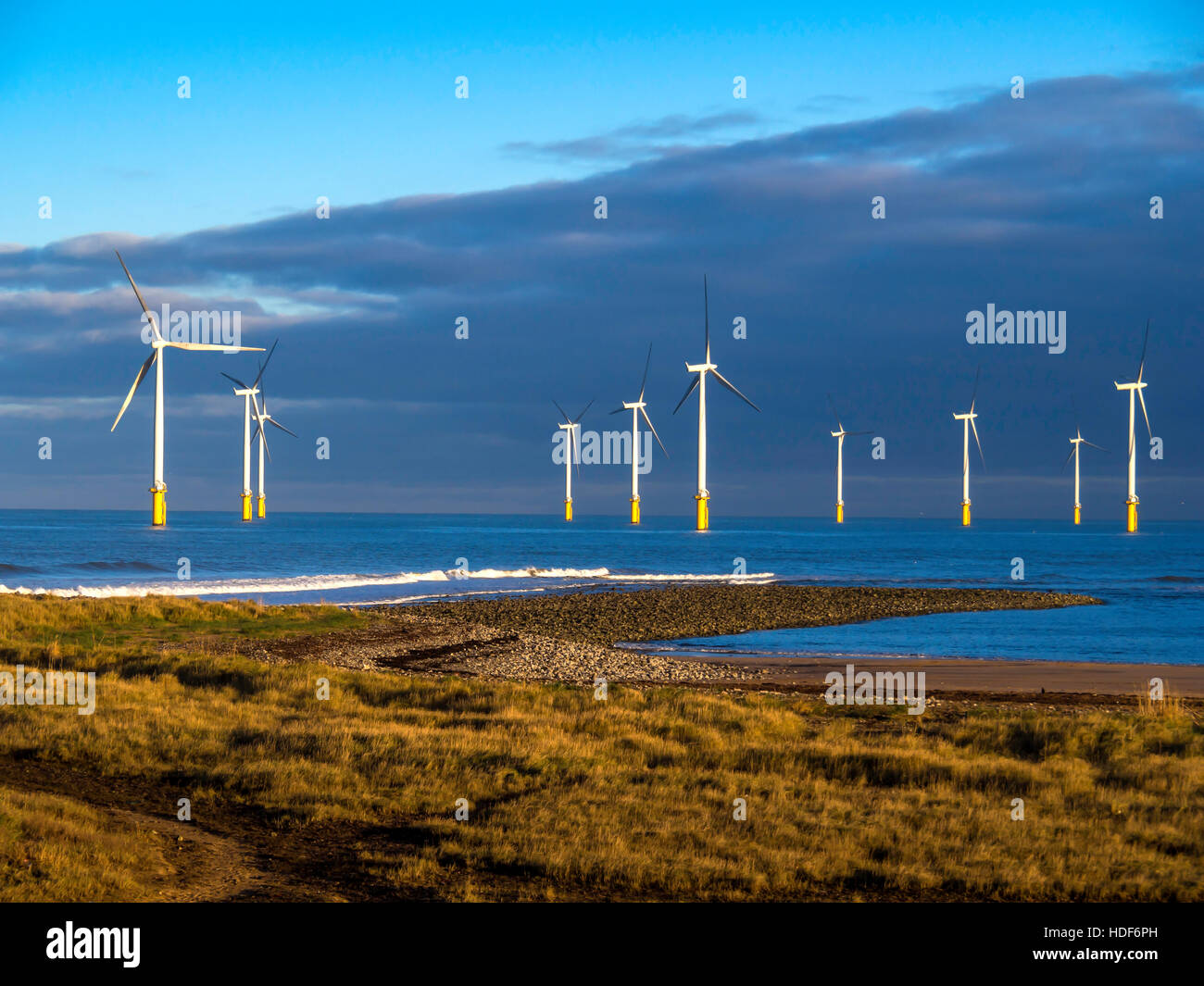 Zehn Turbinen von Sonne beleuchteten Redcar Windpark vom Strand im Abendlicht Stockfoto