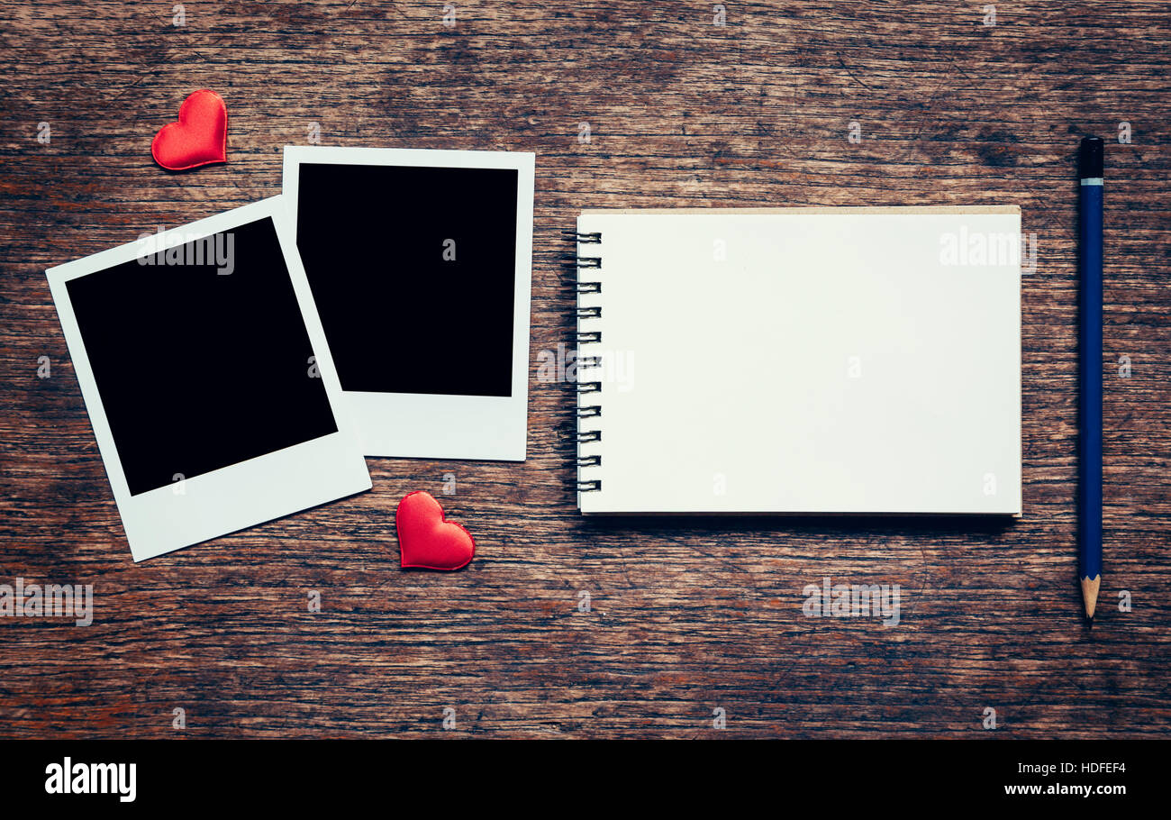 Leere Foto Frame, Notebook, Bleistift und Rot Herz zum Valentinstag auf Holztisch Hintergrund. Stockfoto