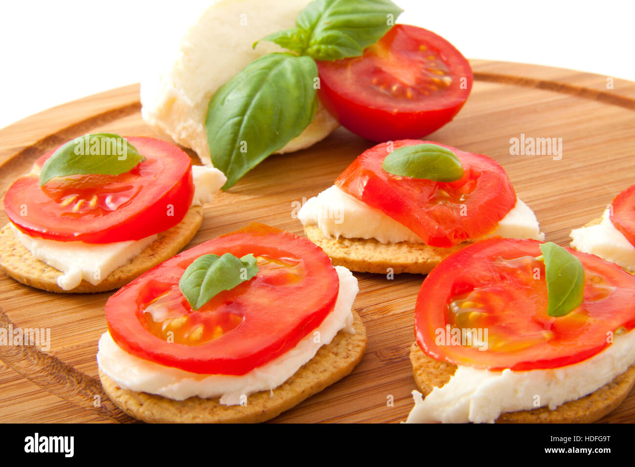 Italienische Tapas mit Käse Tomate und Basilikum auf einer Holzplatte Stockfoto