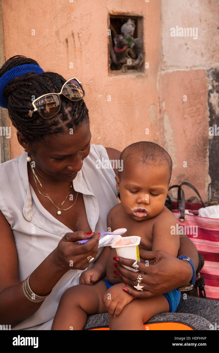 Eine Frau, füttern ihr Baby Joghurt in Zentral-Havanna, Kuba. Stockfoto