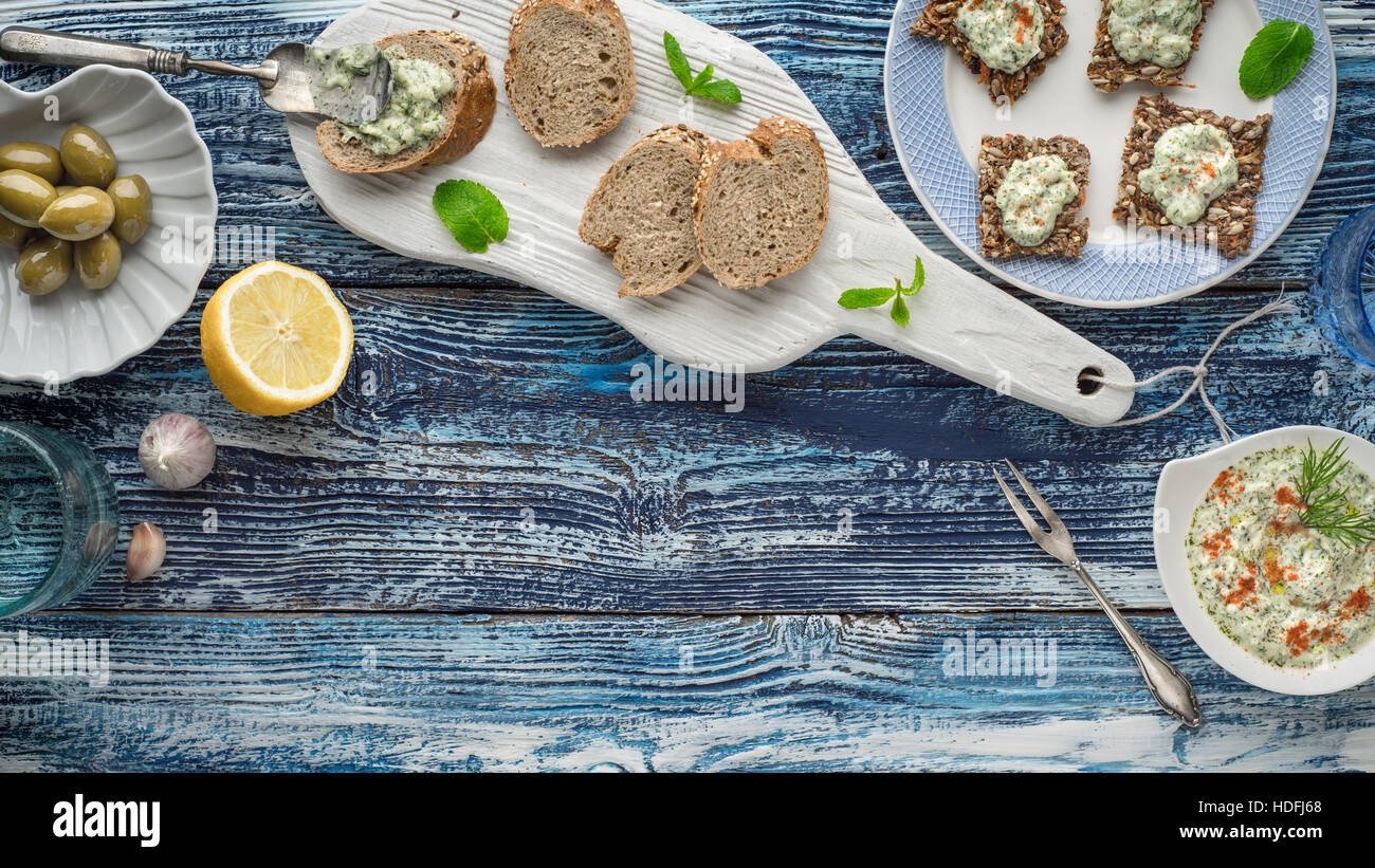 Brot mit Tzatziki auf dem blauen Holztisch mit Zubehör für horizontale Stockfoto