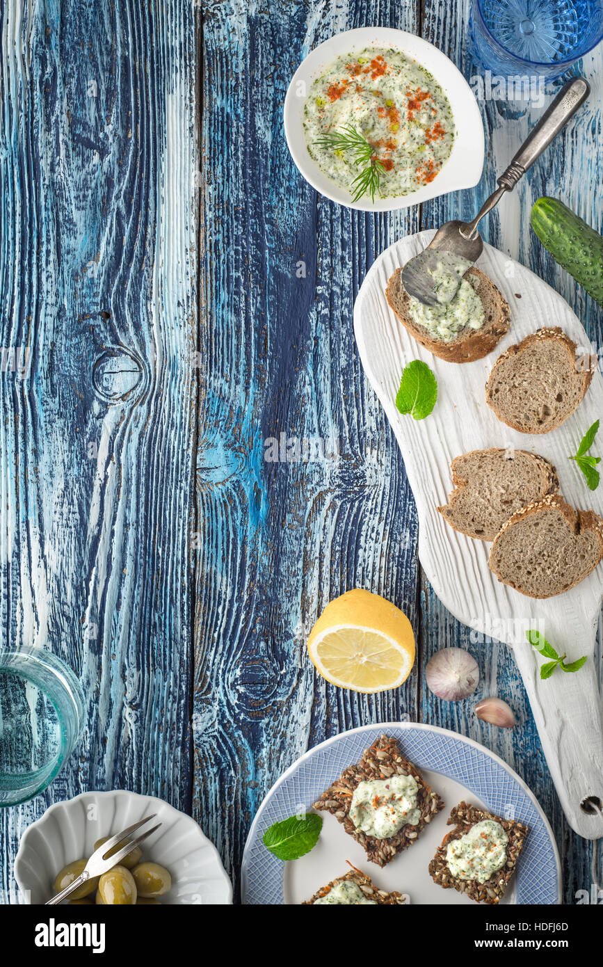Brot mit Tzatziki auf dem blauen Holztisch mit Zubehör für vertikale Stockfoto