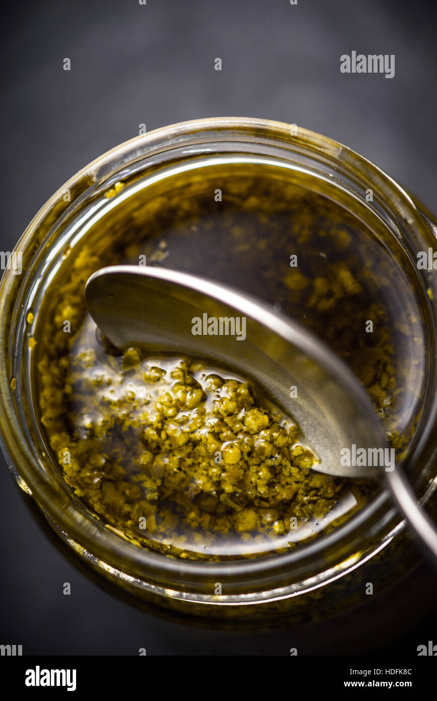Pesto-Soße in das Glasgefäß mit Löffel vertikale Stockfoto