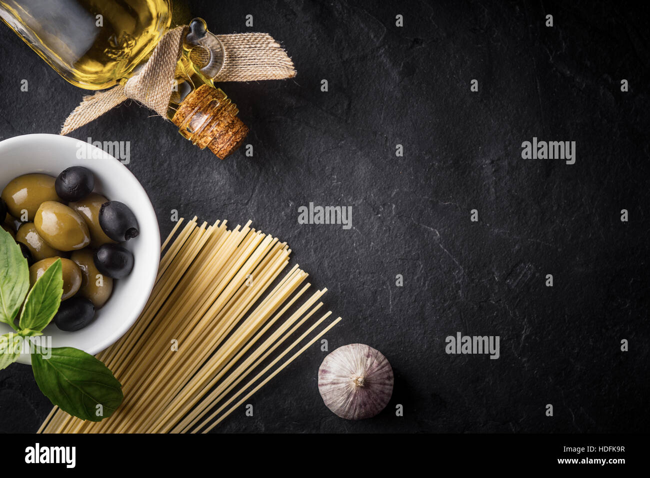 Spaghetti, Oliven und Olivenöl auf dem schwarzen Stein Tisch Stockfoto