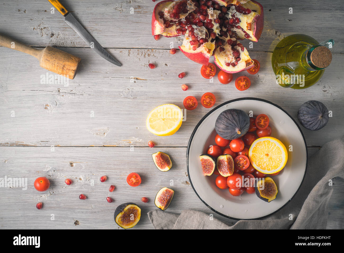 Granatapfel mit Feigen und Kirschtomaten auf der weißen hölzernen Tischplatte-Ansicht Stockfoto