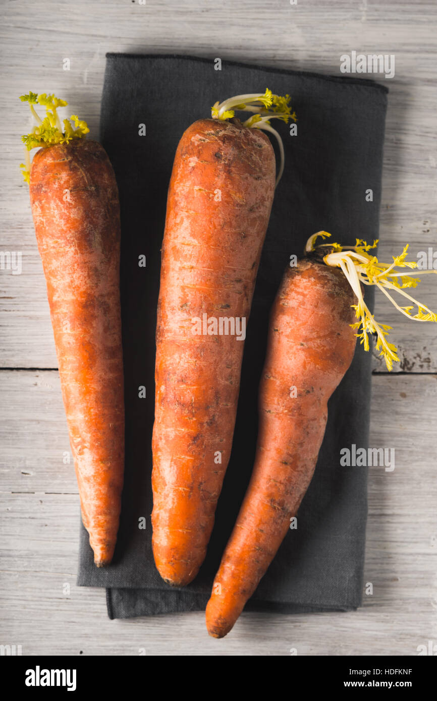 Rohe Karotten auf dem weißen hölzernen Hintergrund vertikale Stockfoto