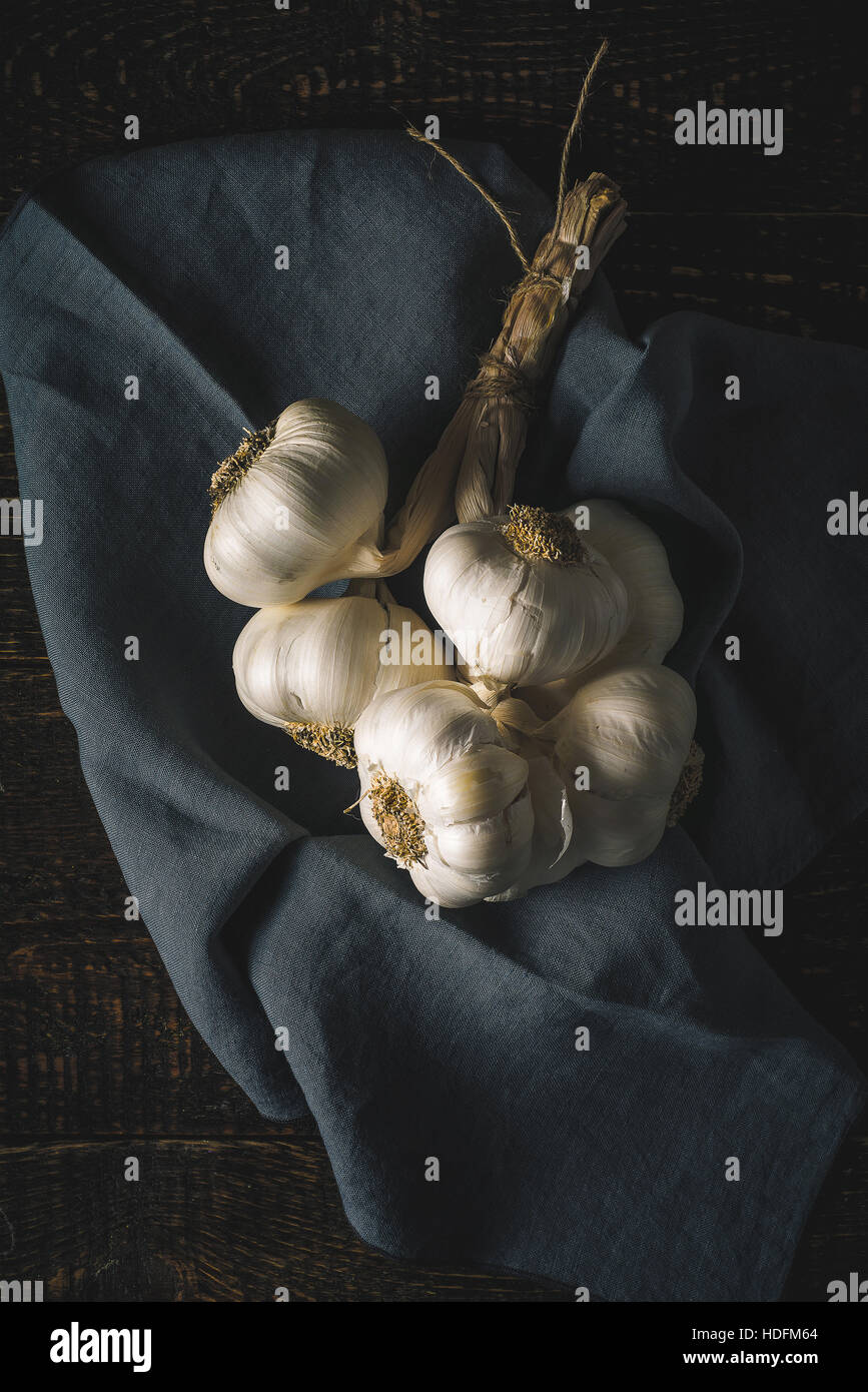 Reihe von Knoblauch mit Serviette auf dem Holztisch vertikale Stockfoto