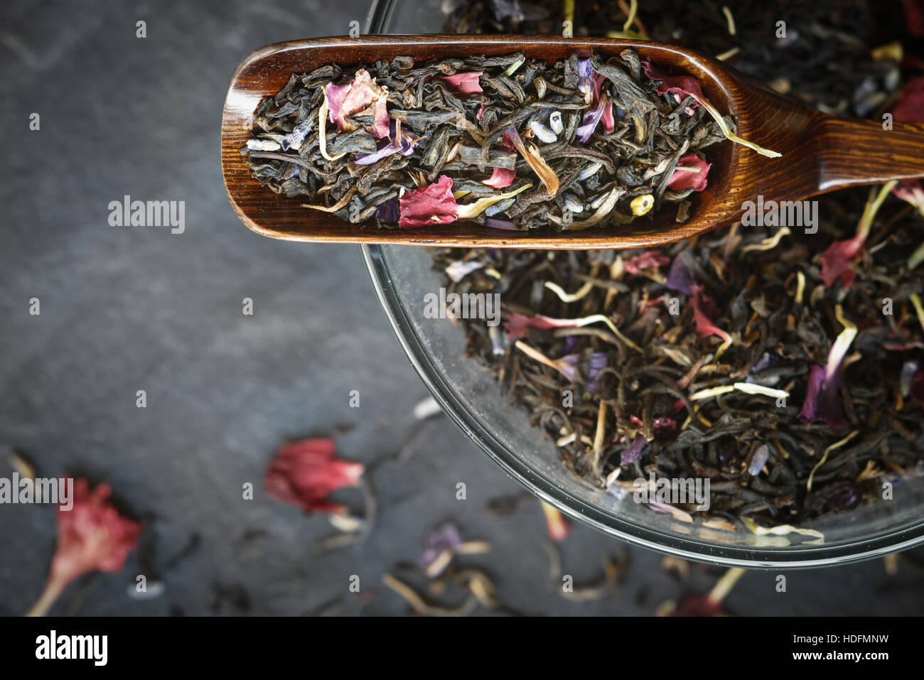 Schwarzer Tee mit Blütenblättern in der Draufsicht Holzlöffel Stockfoto