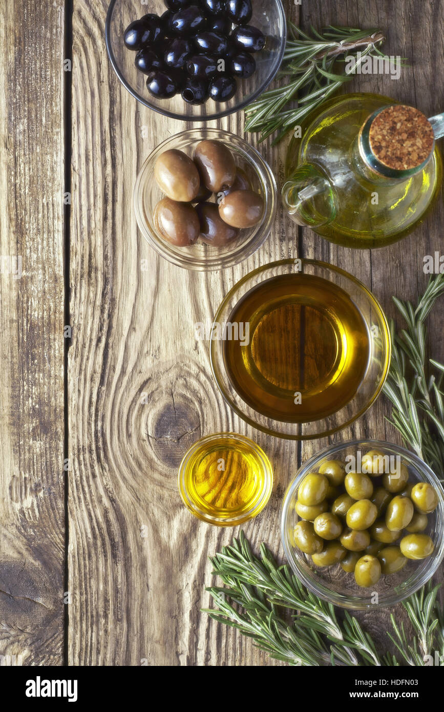 Oliven mit Olivenöl und Rosmarin auf dem Holztisch Stockfoto