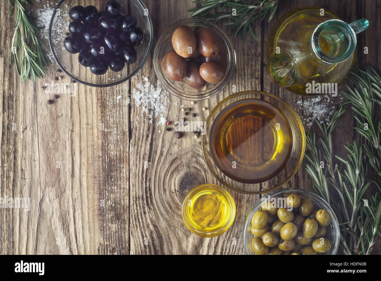 Oliven mit Olivenöl und Rosmarin auf dem Holztisch Draufsicht Stockfoto