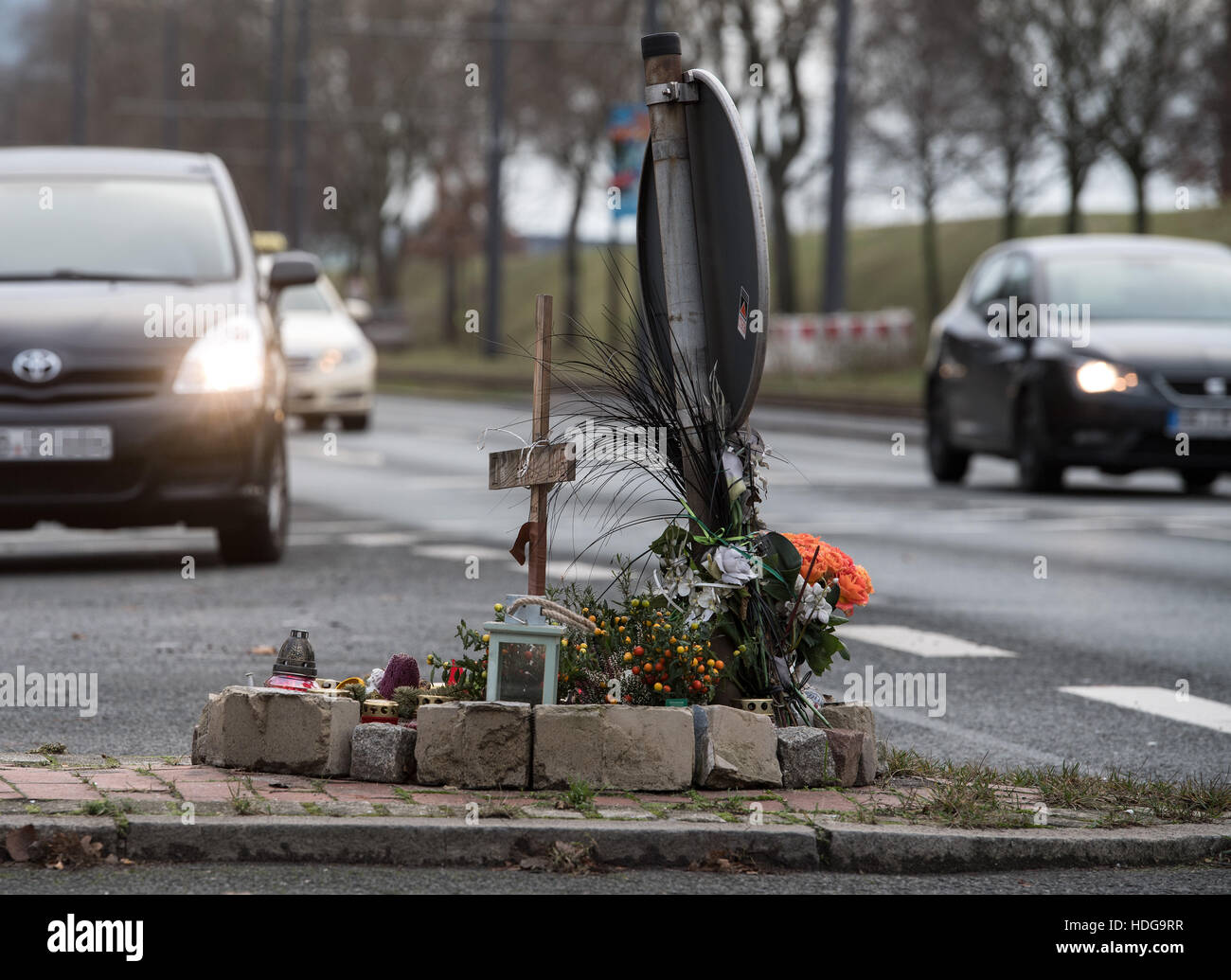 Blumen und ein hölzernes Kreuz erinnern den Tod eines 75-Jahr-alten Mannes, der durch ein Motorradfahrer im vergangenen Juni im Stadtteil Walle in Bremen, Deutschland, 12. Dezember 2016 getötet wurde. Der 24 Jahre alte Biker Gesichter eine Mord Studie aufgrund besonderer Umstände des tödlichen Unfalls, beginnend am 12. Dezember vor dem Landgericht in Bremen. Foto: Ingo Wagner/dpa Stockfoto