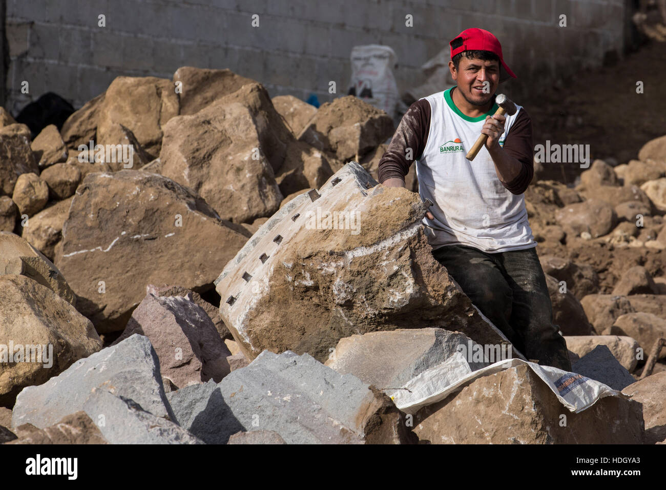 Ein junger Mann teilt große Felsen mit einer kleinen Vorschlaghammer und Stahlkeile in San Pedro la Laguna, Guatemala.  Einige der gebrochenen Rock befindet sich in der foregrou Stockfoto