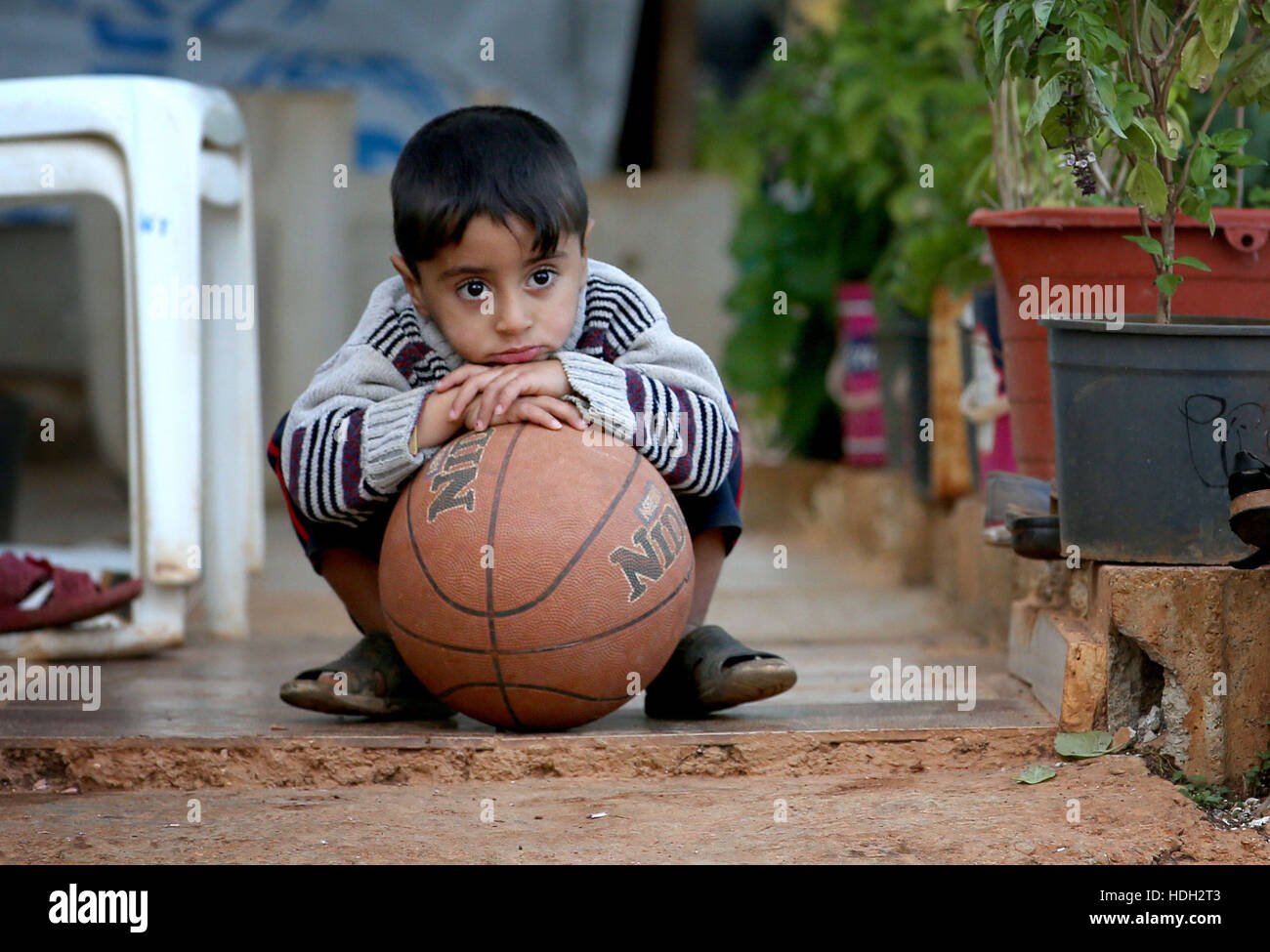 Ein syrischer Flüchtlingskind spielt mit einem Ball in eine Siedlung Camp, wo er unter einem Olivenhain im Koura, in der Nähe von Tripoli, Libanon lebt. Stockfoto