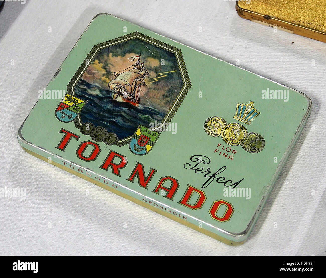 Dieses Bild zeigt eine Zigarrendose zum Sammeln mit dem „Tornado“-Branding. Die Vintage-Dose repräsentiert die Handwerkskunst und Vermarktung von Zigarren im frühen bis mittleren 20. Jahrhundert und bietet einen Einblick in die Geschichte der Tabakverpackung und des Designs. Stockfoto