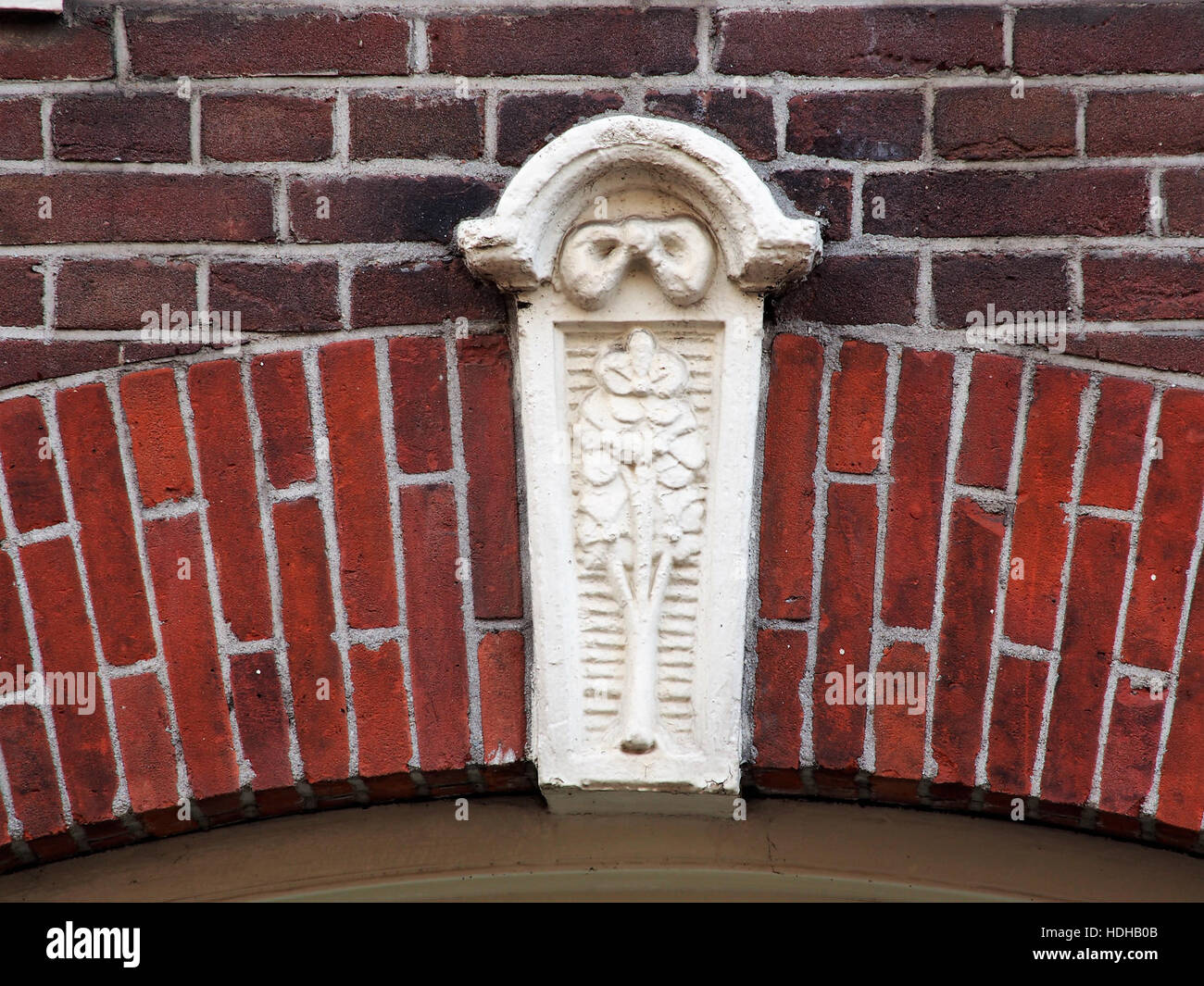 Das Bild zeigt ein detailliertes architektonisches Merkmal, den sluitsteen (Schlussstein), in der Tweede Jan van der Heijdenstraat 42 in Amsterdam. Dieser Schlussstein ist ein wichtiges Element in der traditionellen niederländischen Architektur und markiert die Spitze eines Bogens oder einer Tür. Stockfoto