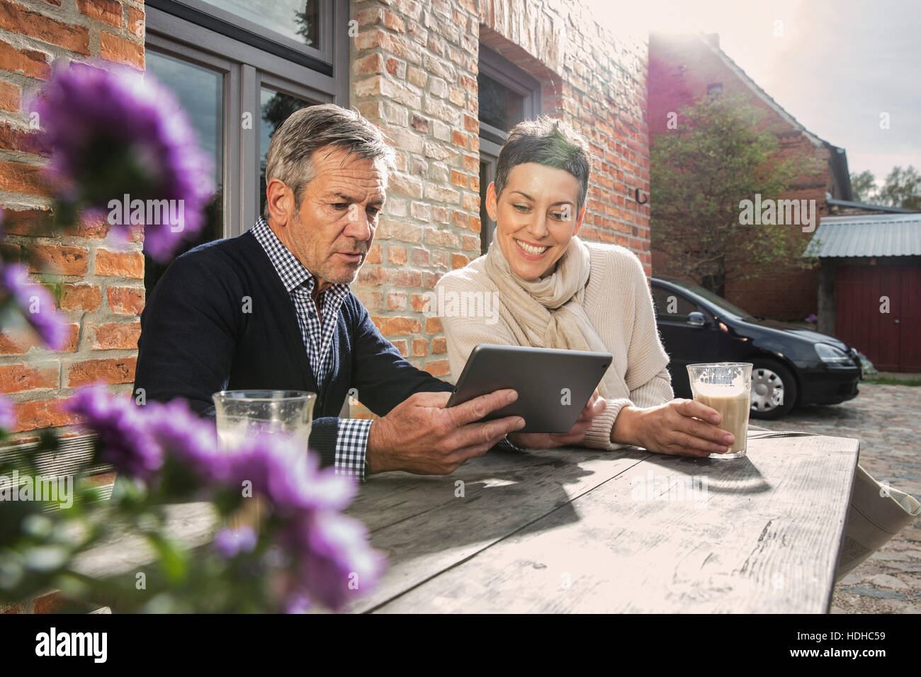 Älteres Paar mit digital-Tablette und Kaffee im Hinterhof sitzen Stockfoto