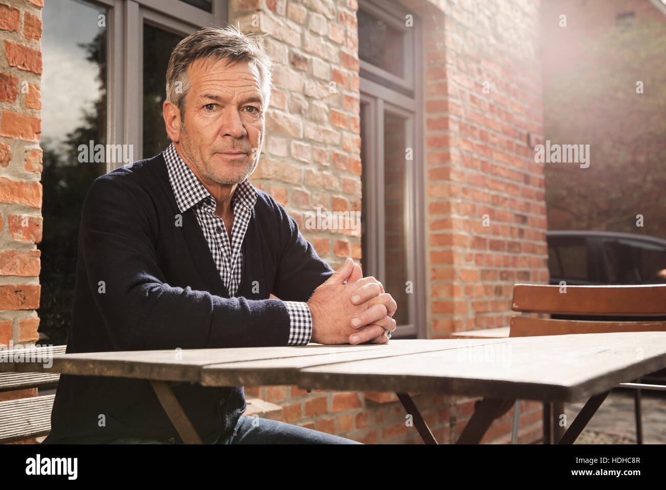 Porträt von reifer Mann sitzt am Tisch vor Haus Stockfoto