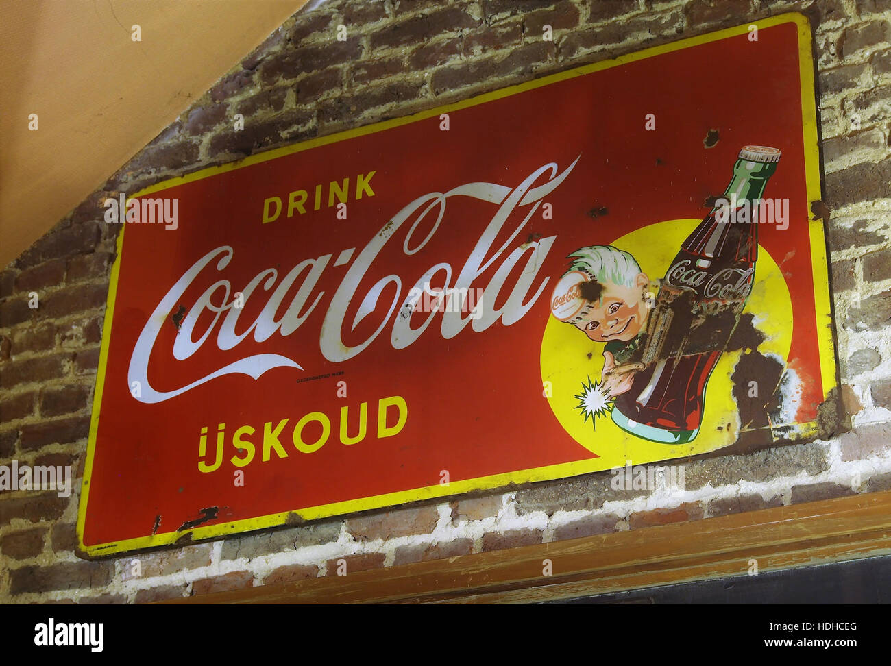 Diese Coca-Cola-Werbung aus Emaille stammt aus dem Winter 1944 und ist in einem Museum in Gingelom ausgestellt. Das Kunstwerk spiegelt die Designtrends der 1940er Jahre und Coca-Colas bedeutende Rolle in der Werbung während des Zweiten Weltkriegs wider, als die Marke für die amerikanische Kriegskultur und -Wirtschaft von zentraler Bedeutung war. Stockfoto