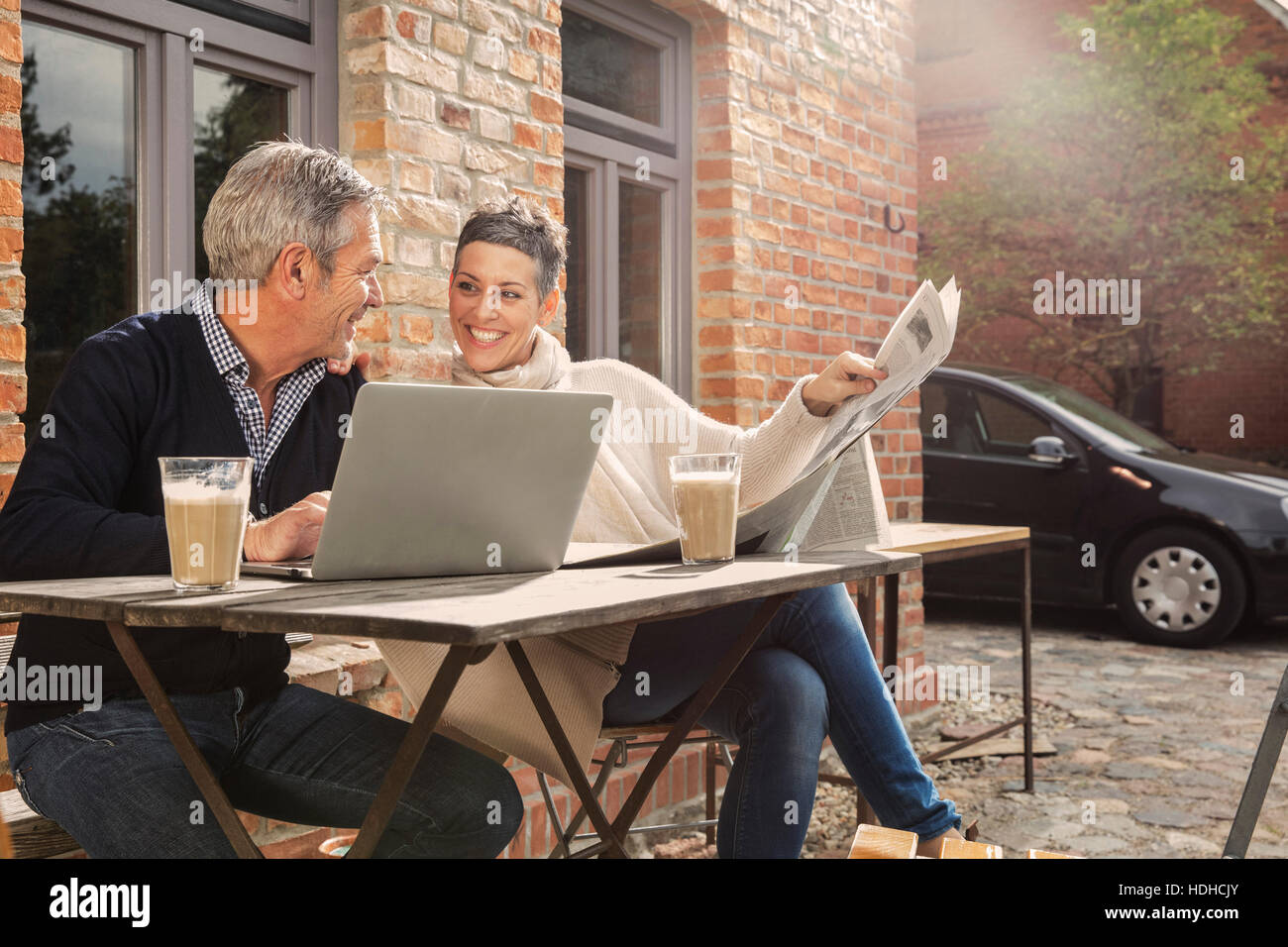 Gerne älteres paar Zeitunglesen mit Laptop im Hinterhof Stockfoto