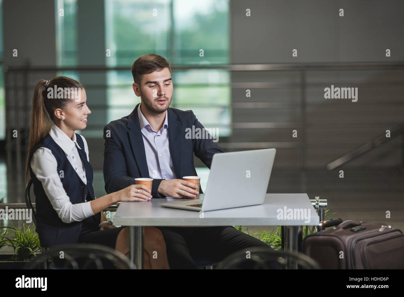 Junger Geschäftsmann mit Kollegin mit Laptop am Tisch im Flughafen Stockfoto