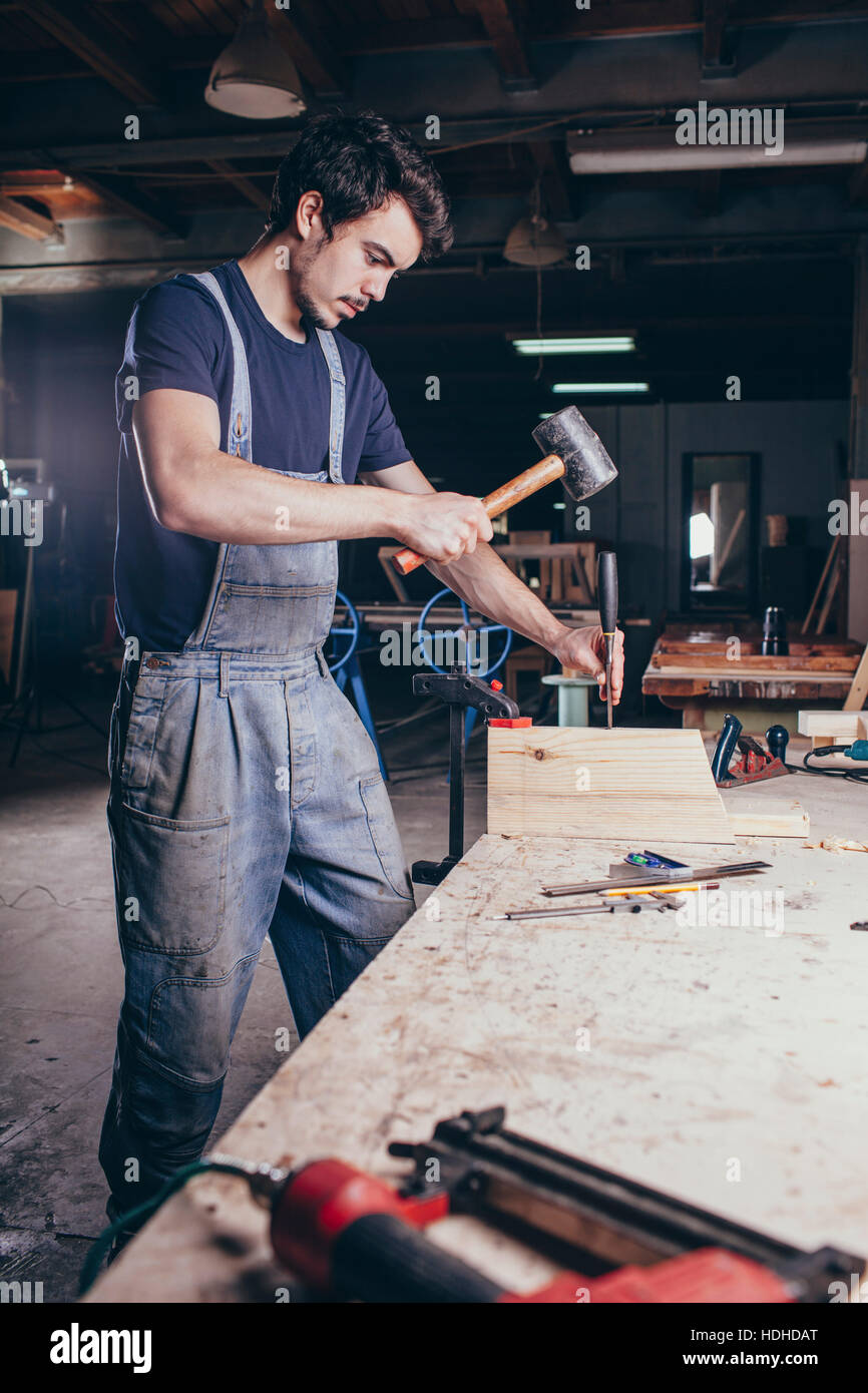 Tischler mit Hammer und Meißel auf Holz in Werkstatt Stockfoto