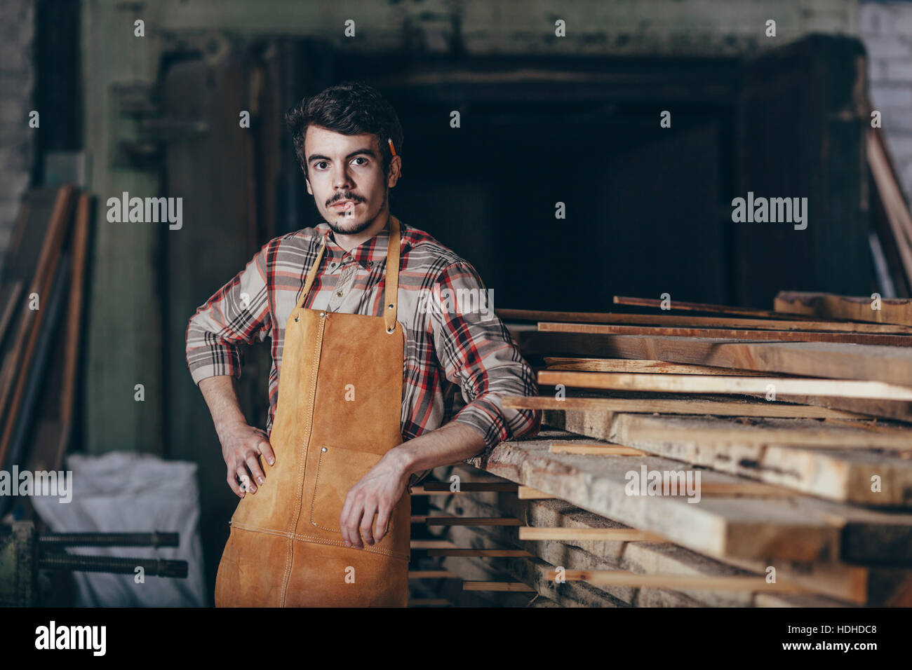 Porträt von Zimmermann steht Holz Stapel in Werkstatt Stockfoto