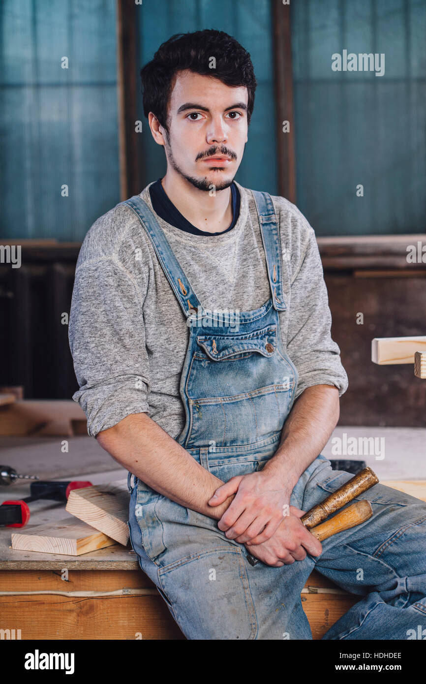 Porträt der jungen Arbeitnehmer mit Handwerkzeugen auf Bank sitzend Stockfoto
