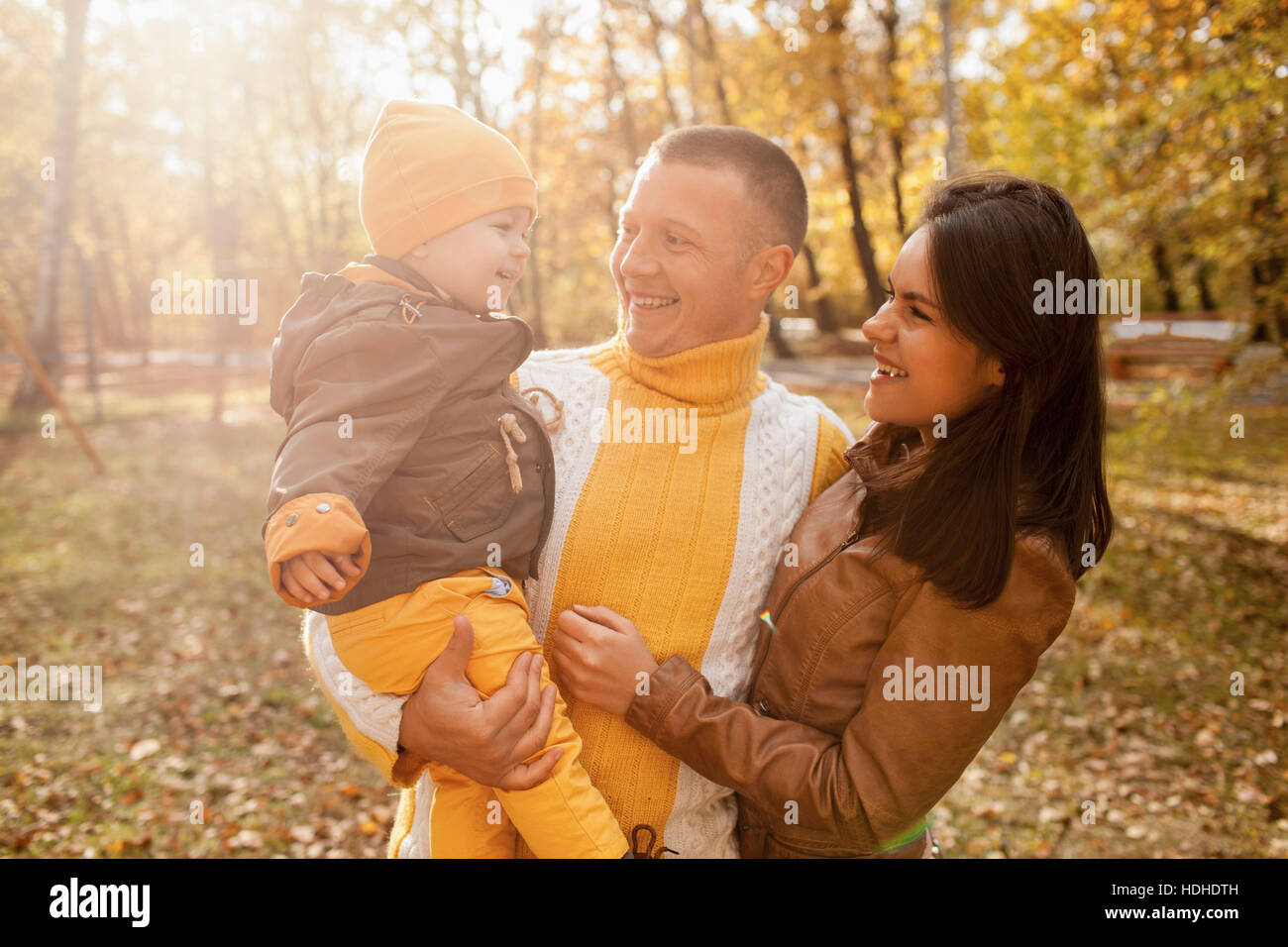 Fröhliche Eltern betrachten Sohn stehend im Park im Herbst Stockfoto
