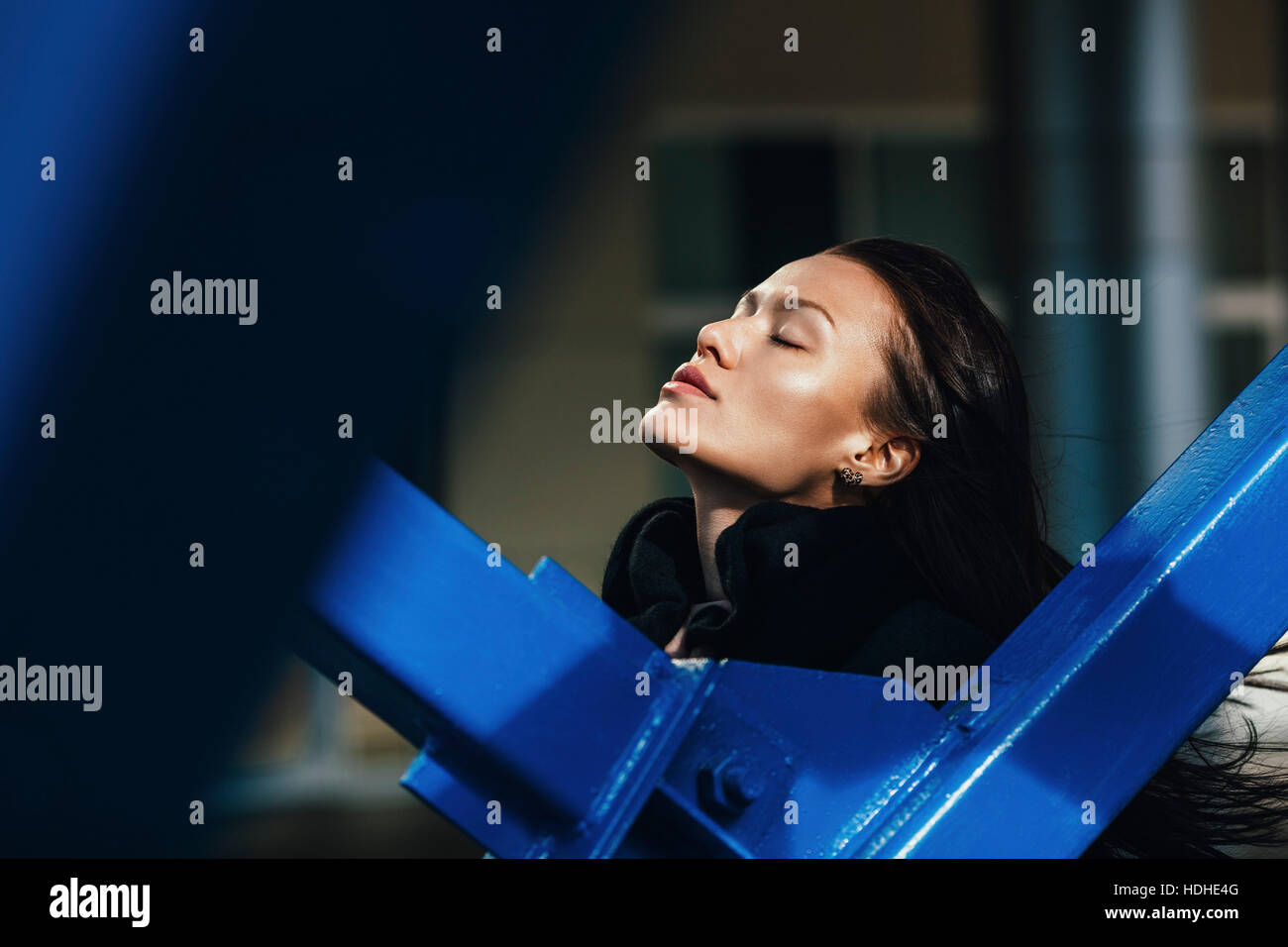 Einsamkeit-Frau mit Augen von Metallgeländer an sonnigen Tag geschlossen Stockfoto