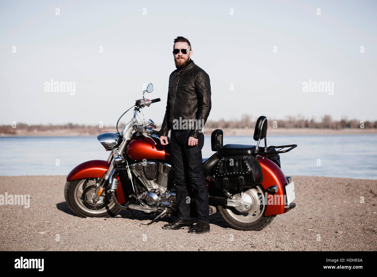 In voller Länge Portrait von Biker mit dem Motorrad am Ufer stehen Stockfoto