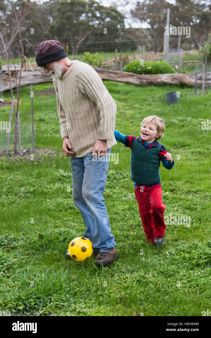 Gesamte Länge der Großvater und Enkel Fußball spielen auf der Wiese Stockfoto