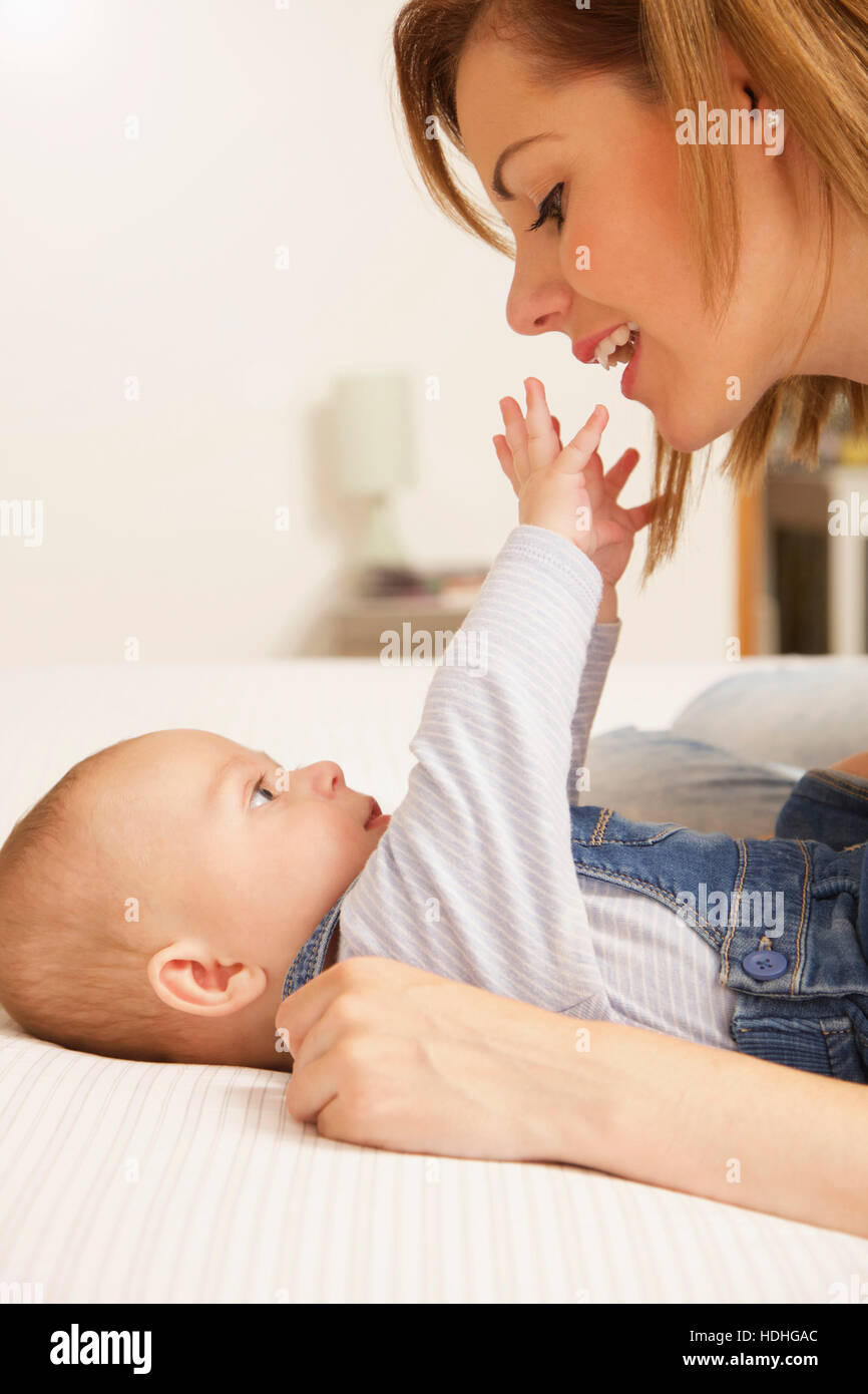 Niedliche Baby-jungen erreichen Hände in Richtung Mutter liegend im Bett zu Hause Stockfoto